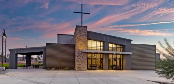 Steel church building with cross at sunset